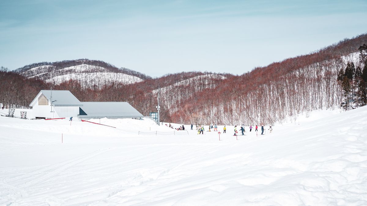 Winter scene at Yuzawa ski resort in Japan with snow-covered slopes and skiers enjoying the day.