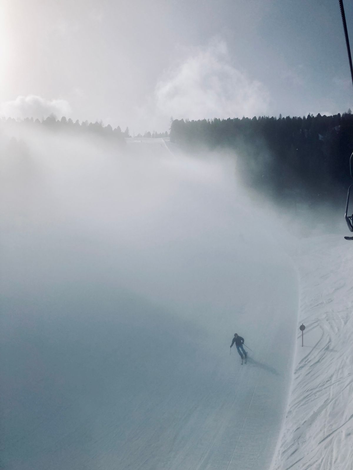A skier descends a fog-laden slope in winter, emphasizing the thrill of winter sports amidst snowy landscapes.