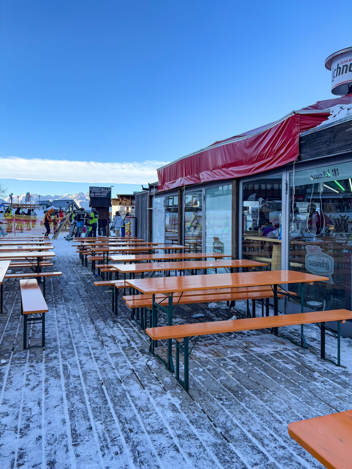 Outdoor seating at a ski resort in the Italian Alps, with snow and mountains in view.